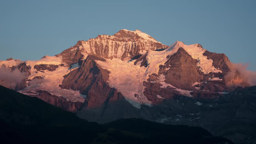 Time lapse of clouds forming around a snow covered mountain