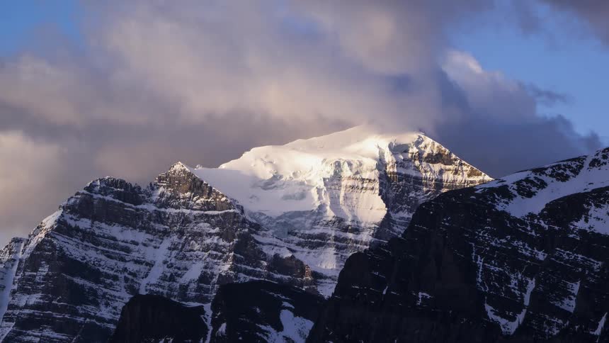 Clouds pass over a frozen mountain in the Rocky Mountains in Canada