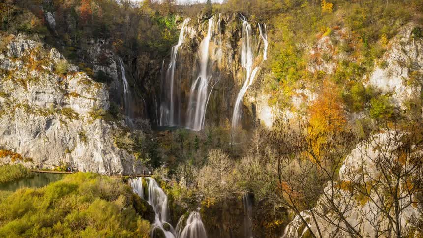 The grand waterfall in Plitvice National park with visitors walking on a bridge
