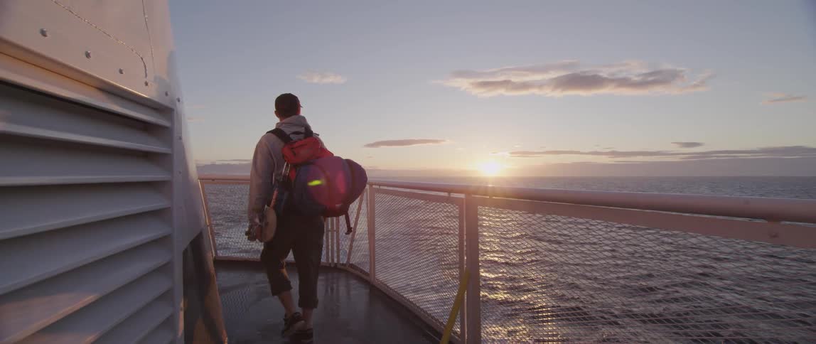 A man looks at the ocean from a ship deck
