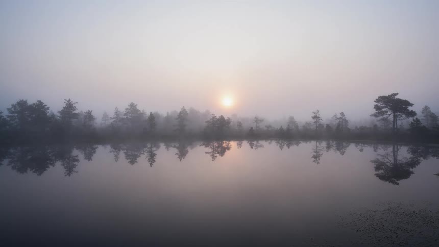 Time lapse of the sun rising over a foggy lake