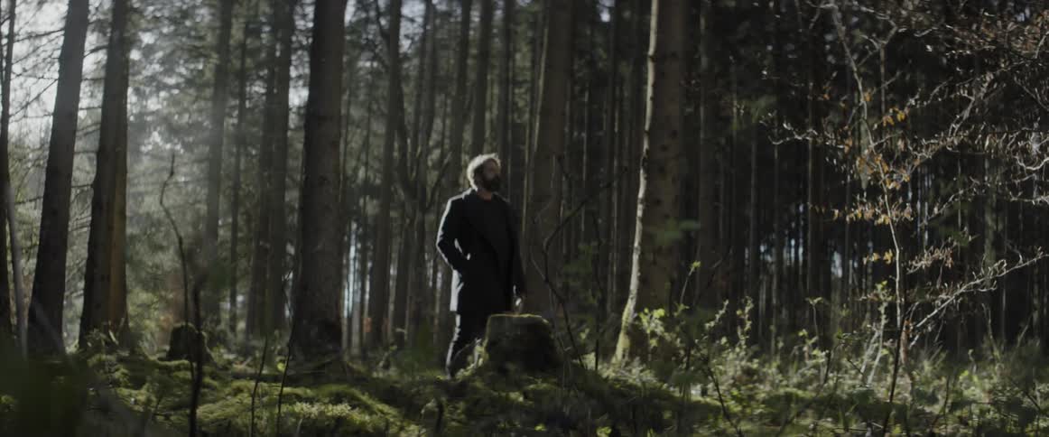 A man in a coat is walking in the forest