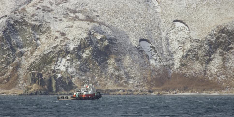 A tugboat sails along the coastline