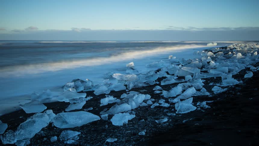 Chunks of ice sit on the beach as waves come to shore