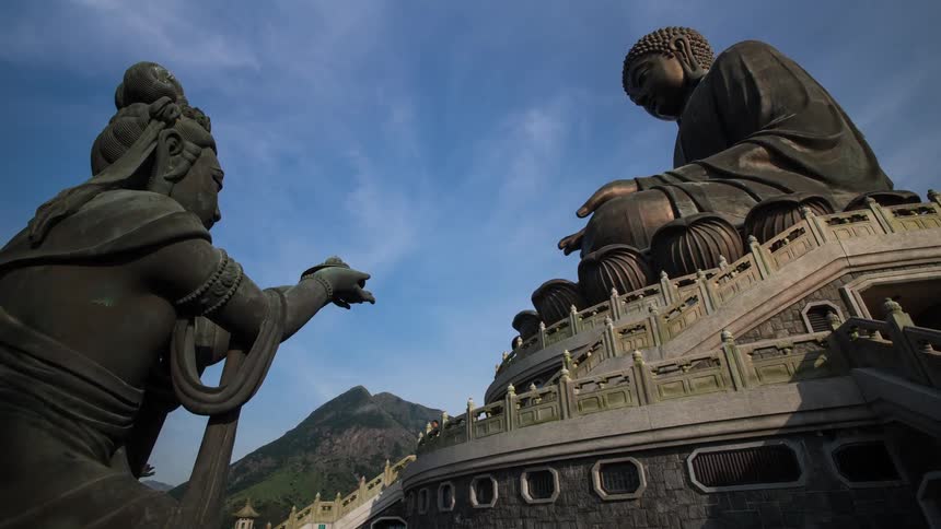 People climb stairs near buddhist statues during the day