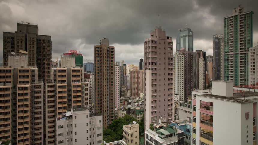 Storm clouds are moving across a city throughout the day