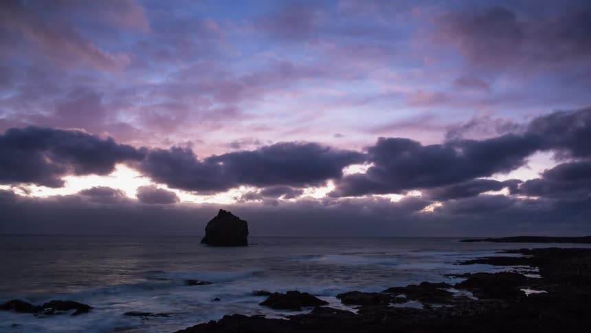Clouds are drifting over a beach at dusk