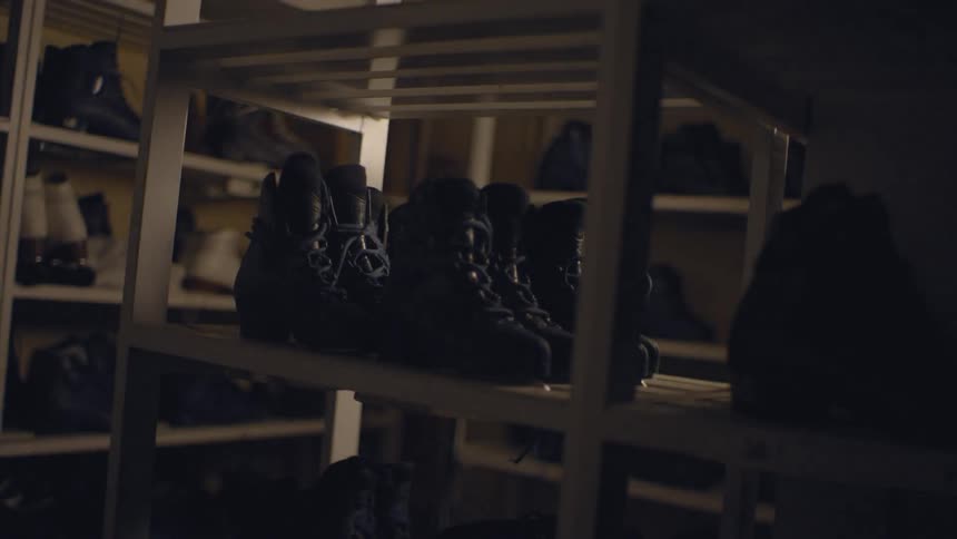 Shoes are displayed on shelves in a room with a blinking light