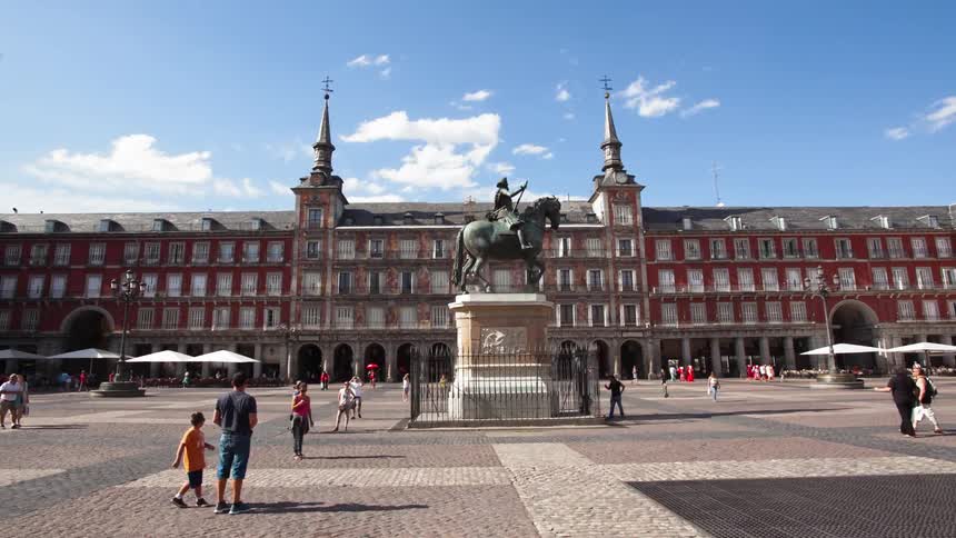 People are walking through an old city square during the day