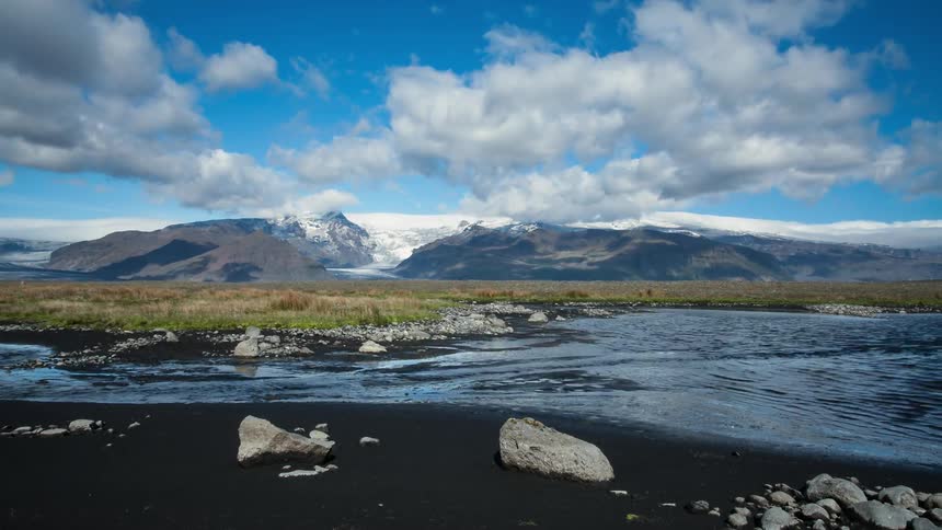Clouds pass over mountains and a flowing stream