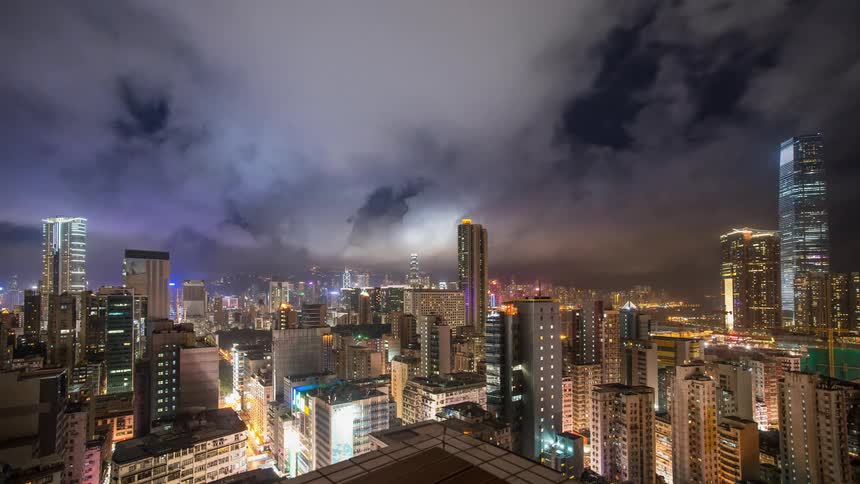 Clouds are drifting over the tops of skyscrapers in Hong Kong during the night