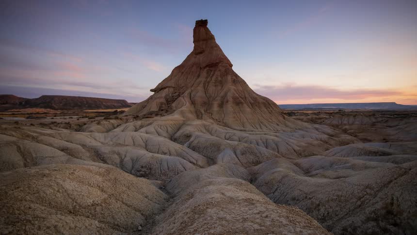 The sun rises over rock formations in the desert