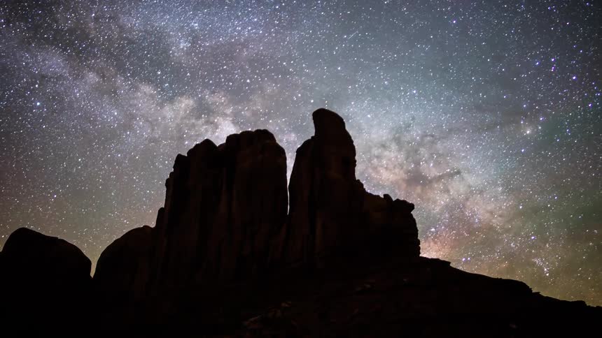 Time lapse of the starry sky at night above some large desert rocks