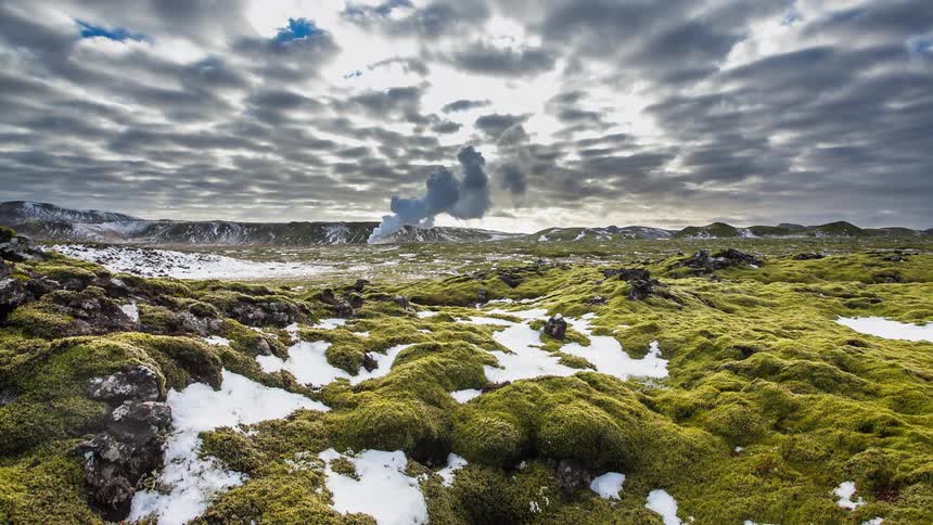 Steam is rising from hot springs in a natural landscape on a cold day