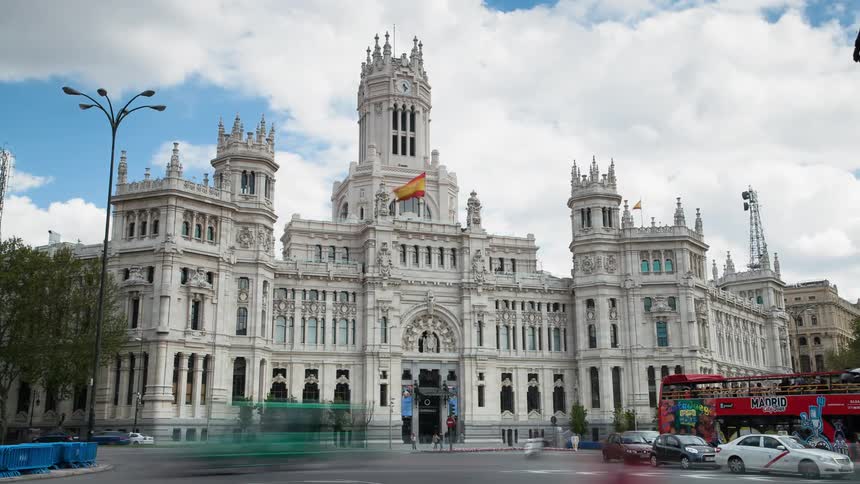 Vehicles and pedestrians pass by a city center landmark building