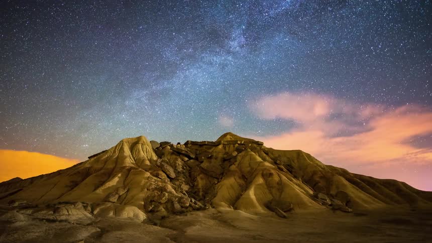 Clouds and stars pass over a desert mountain