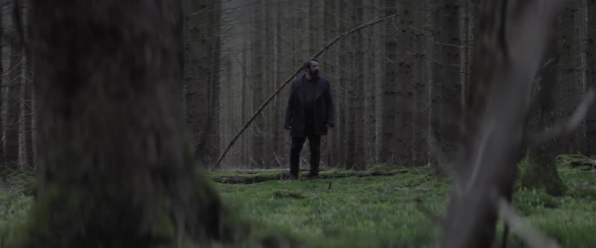 A man is wandering around the woods and looks lost