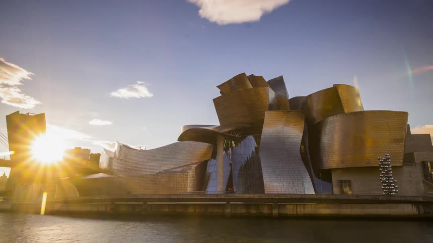 The sun rises above a city canal and architectural building