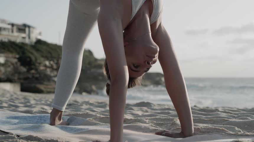 Woman practices yoga on the beach