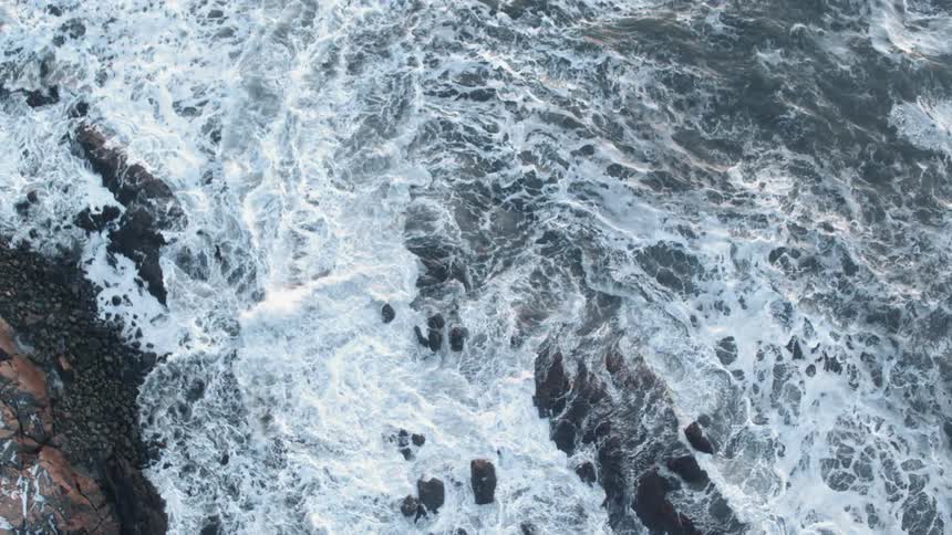Waves are crashing into some large rocks