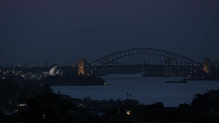 A city bridge spans a river at night