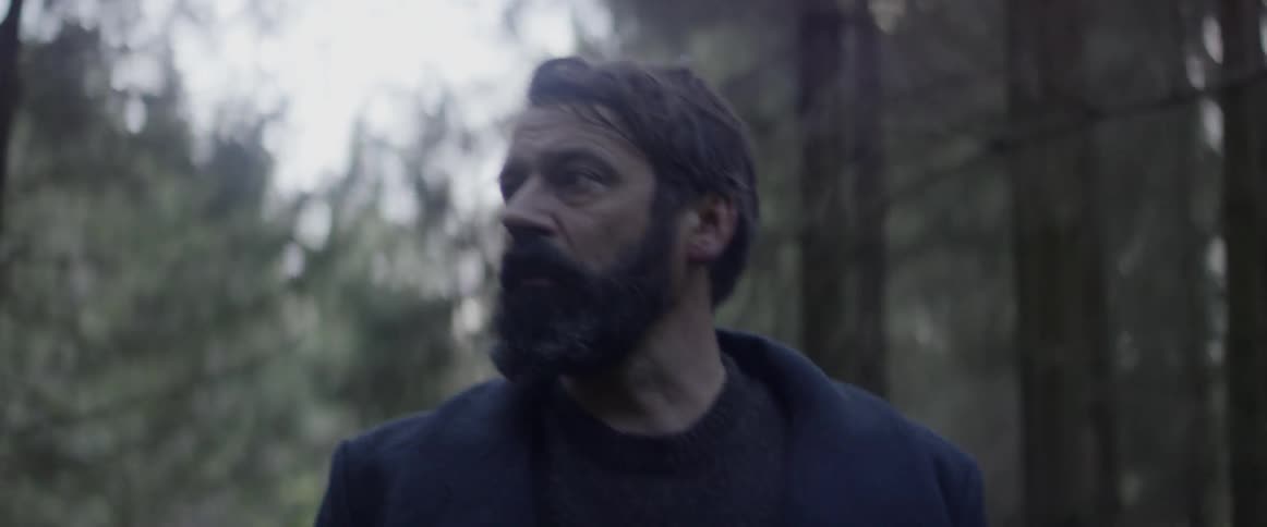Man looks worried while walking alone in a forest