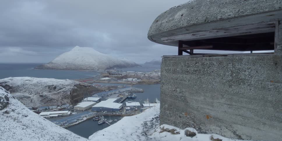 A bunker sits on a snowy hill overlooking a port
