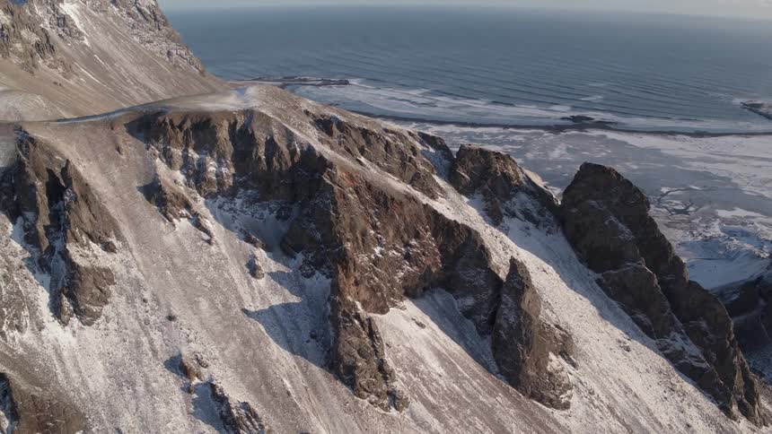 Snow covers a coastal mountainside