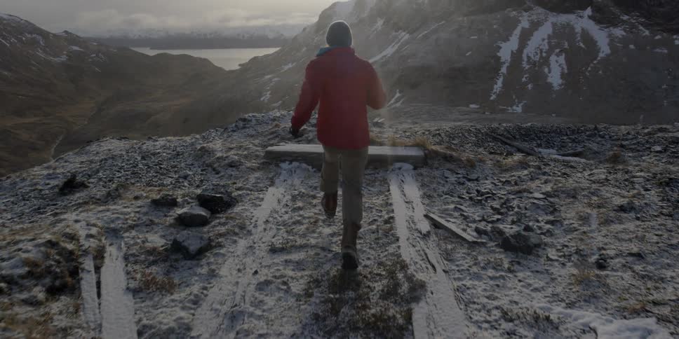 Man runs and leaps over snow in mountains