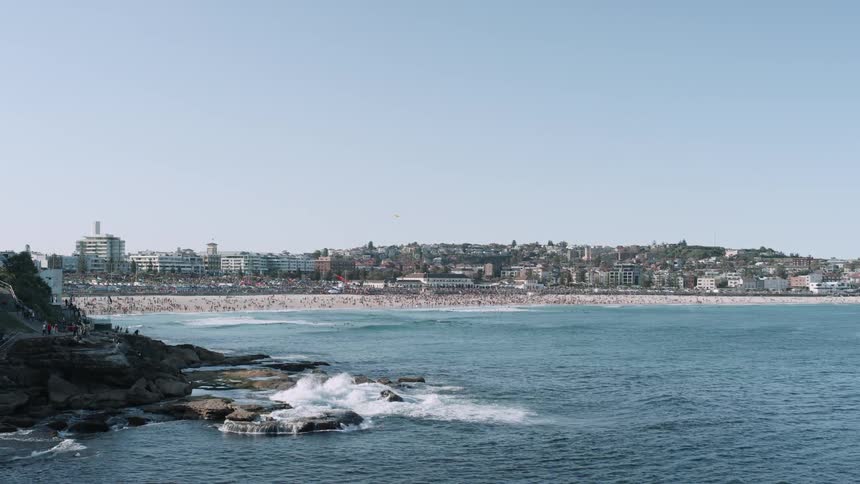 The waves crash near the rocks by the beach
