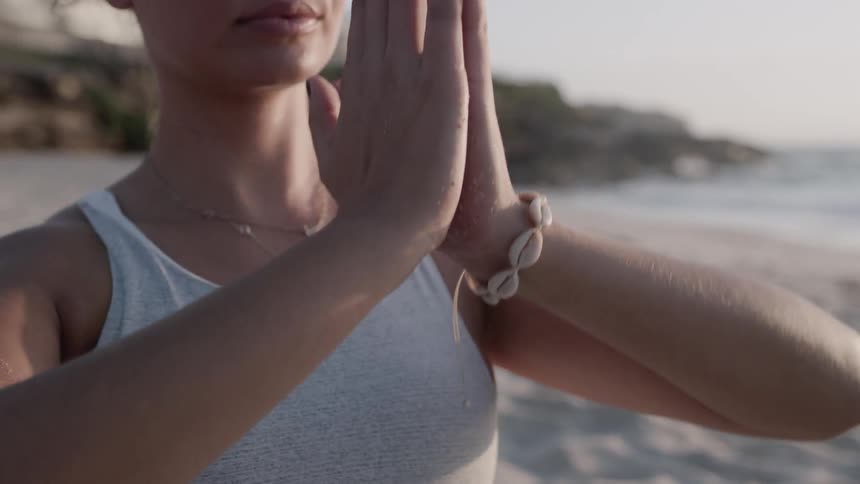 A woman does yoga on a beach at sunset