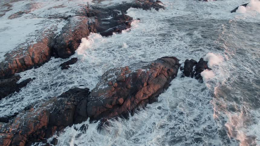 Water splashes up on large rocks on a sunny day