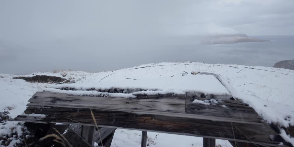 Snow blows over an old wooden structure
