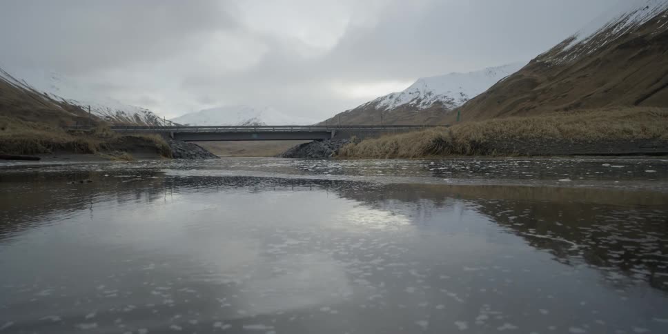 Water flows gently from under a bridge in the distance