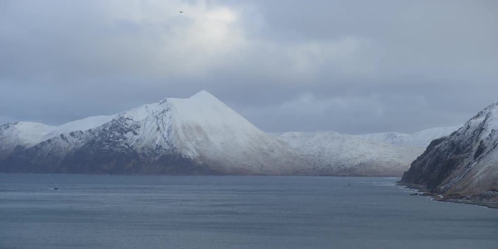 Fog rolls over the mountains by the water