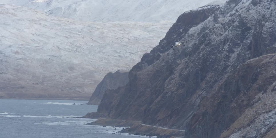 An airplane flies near a rocky mountainside