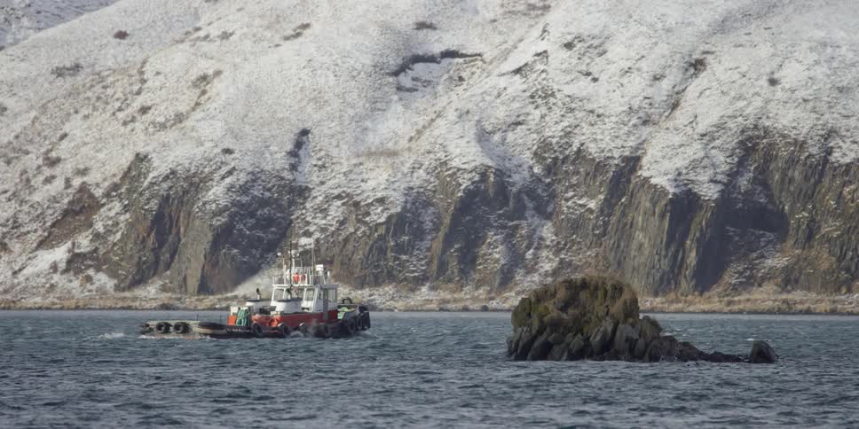 Boat moving on some cold water next to large rocky terrain