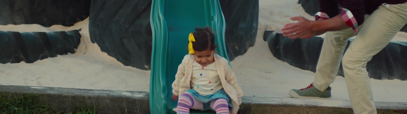 A small girl playfully rides down a slide