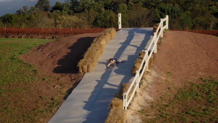 A child slides down a hill on a farm