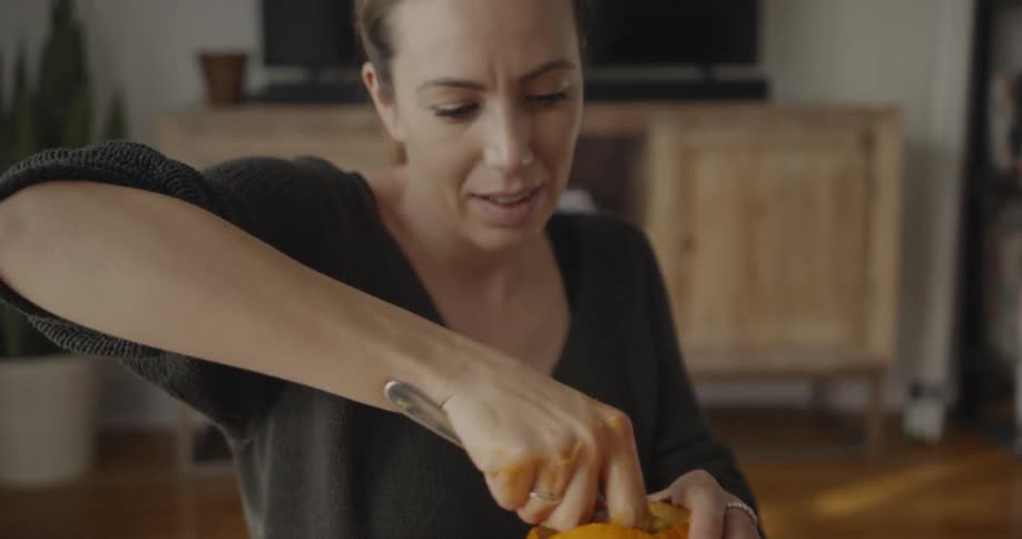 A woman carves pumpkins at home