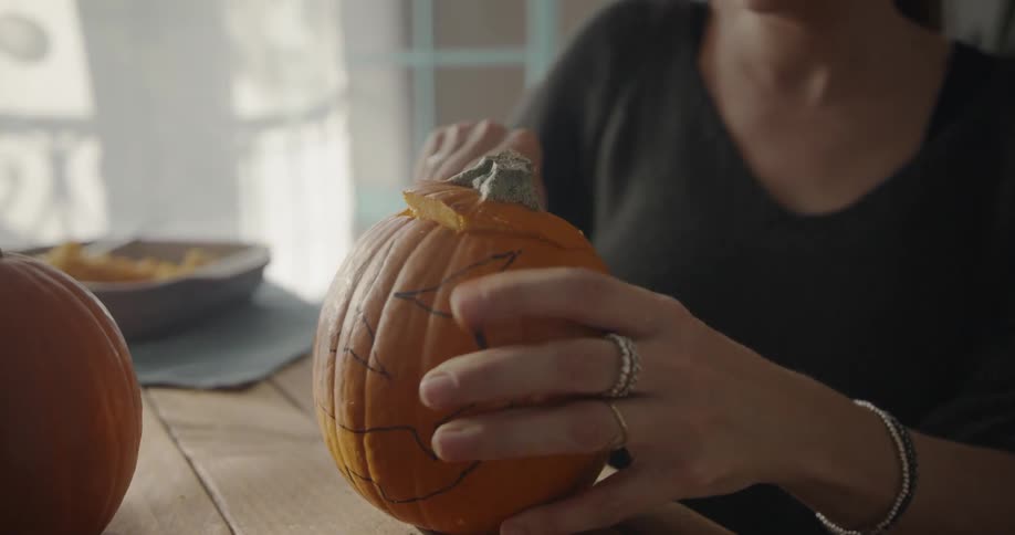 A woman removes the top off a pumpkin