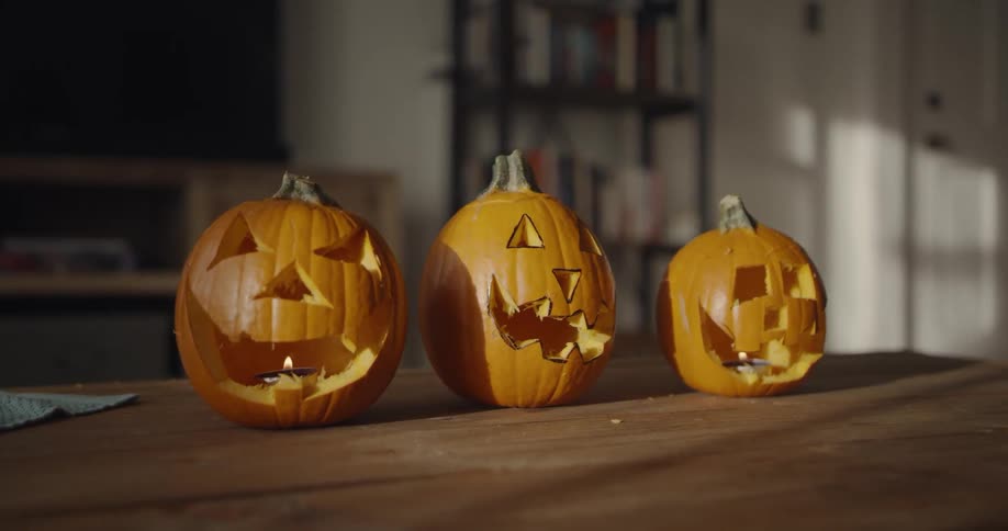 Three jack o'lanterns are sitting on a table