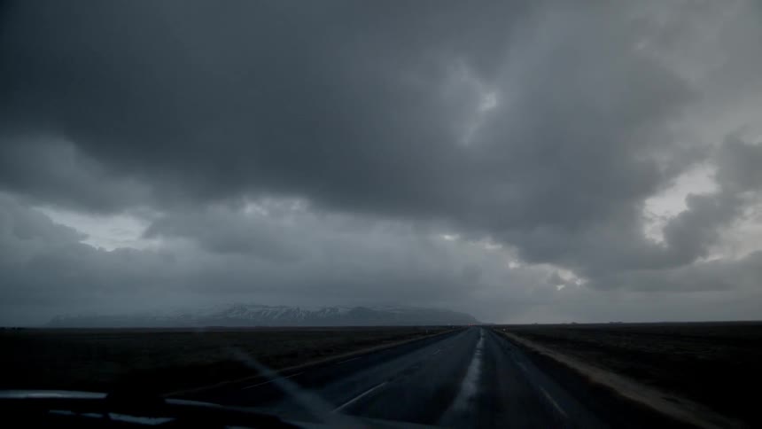 A car is driving down an empty flat road