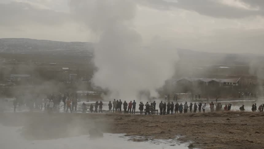 People are standing around watching a hot springs geyser explode
