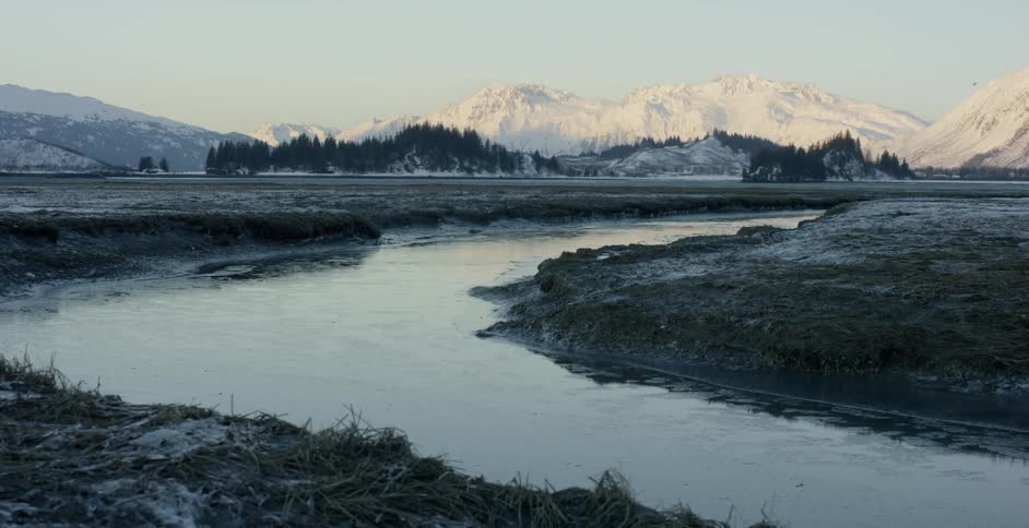 Ice is floating in a river flowing through a mountain valley at dawn