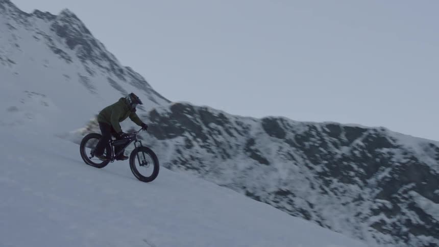 A man rides a bicycle through the snow