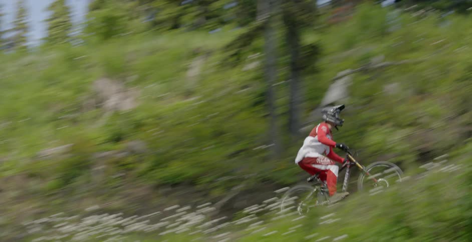 A bicyclist goes over a jump in a forest