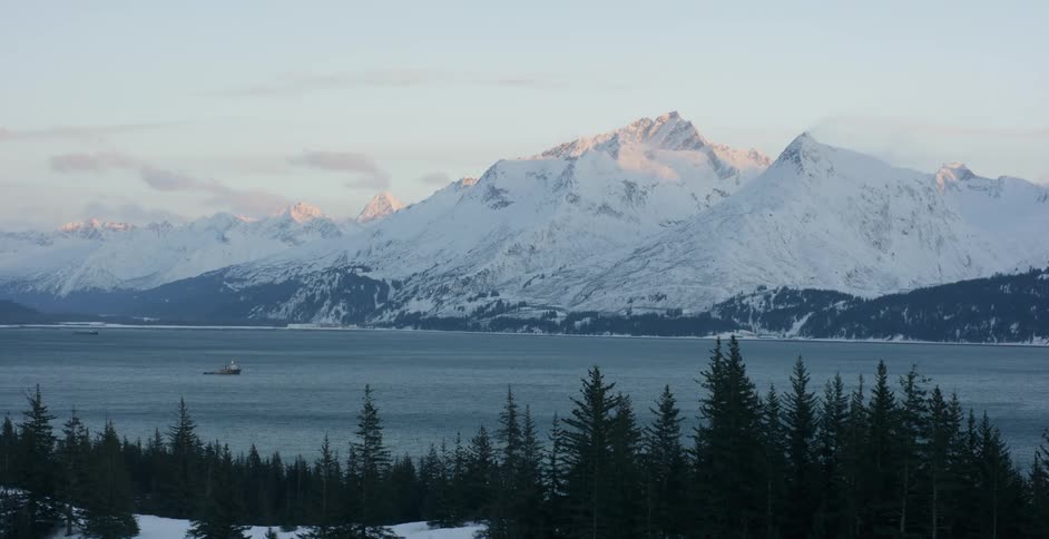 Snowy mountains surround a lake at sunset