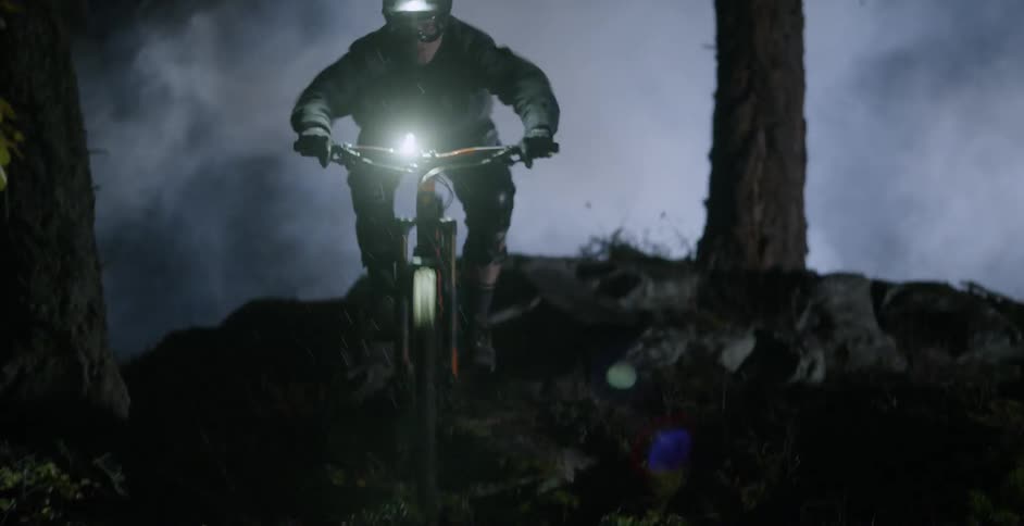 A bicyclist rides through a dark forest