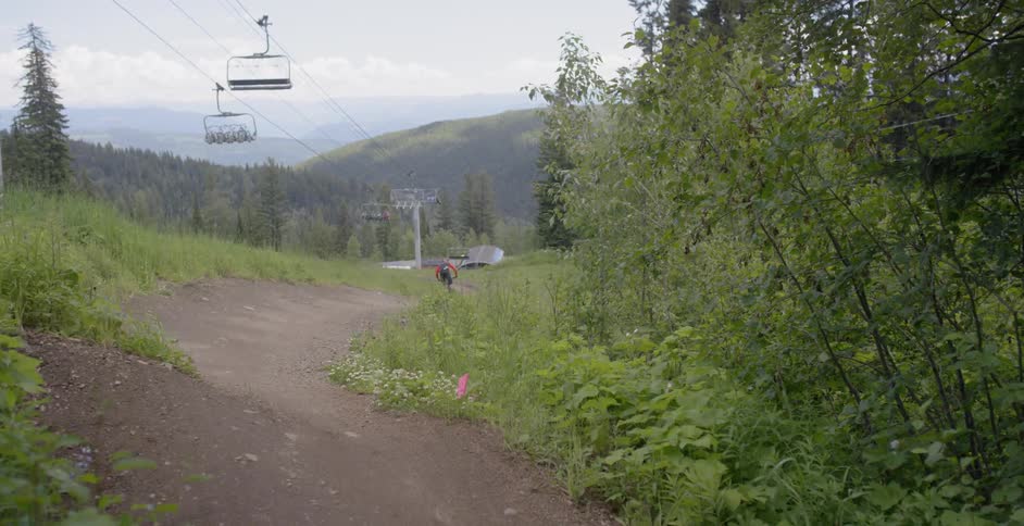 A rider does a jump as they ride a bike on a dirt path in a natural setting during the day